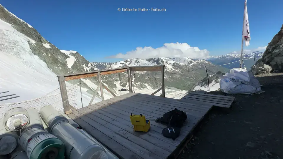 Drone et matériel sur la terrasse d’une cabane, face aux montagnes enneigées